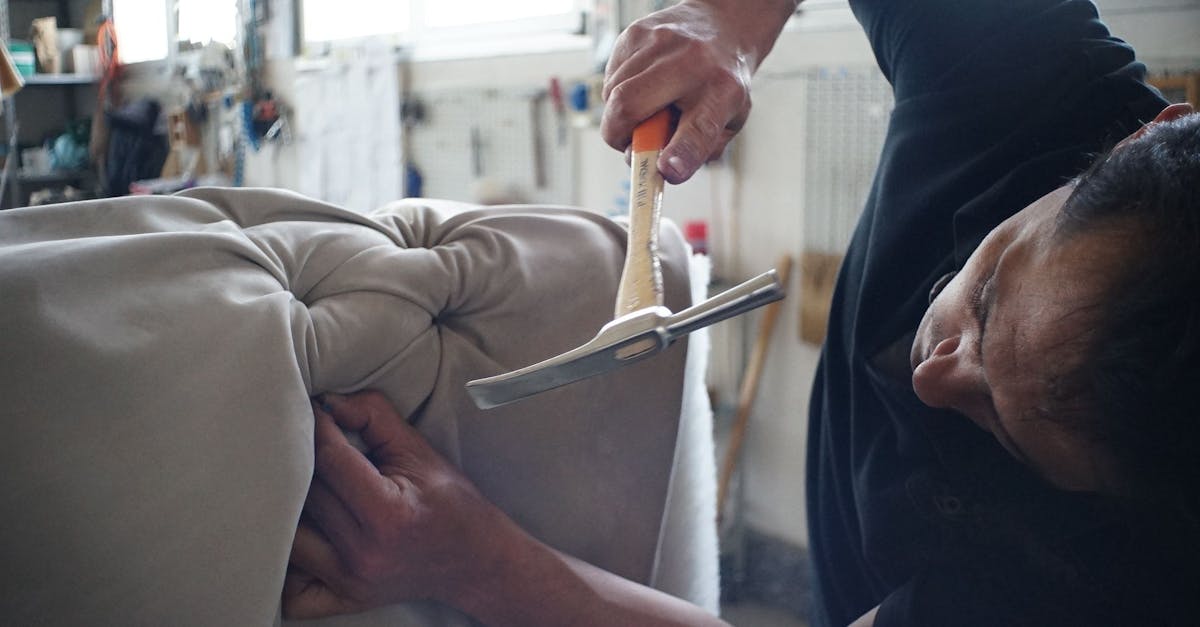 Skilled artisan working meticulously on a sofa using upholstery tools in a workshop.