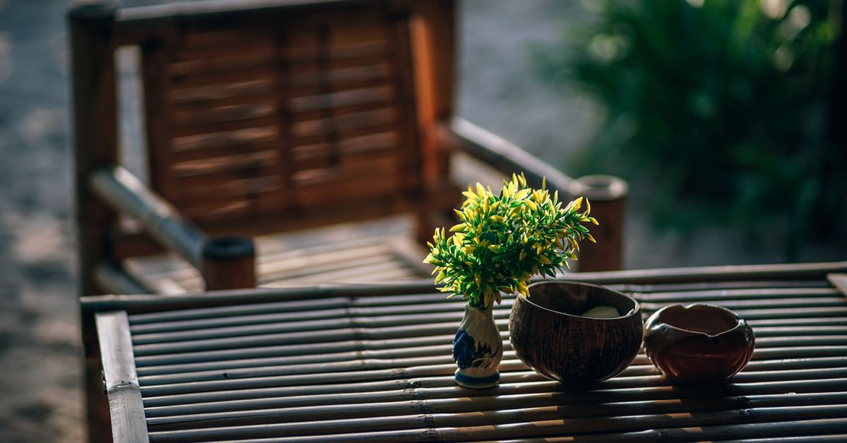 Serene bamboo seating arrangement with vase and greenery in a Thai garden setting.