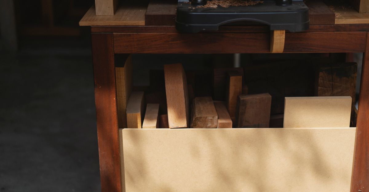 Professional electric equipment for woodwork and shavings above different wooden pieces in workshop in daytime