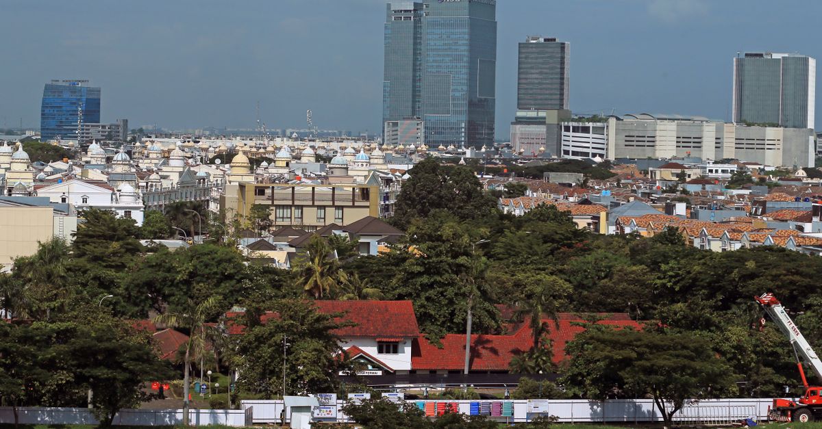 A vibrant cityscape featuring towering skyscrapers and lush greenery under a blue sky.