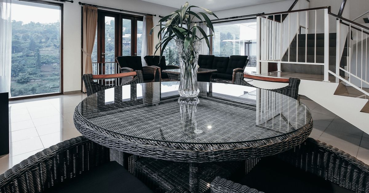 Stylish dining room in Bandung with wicker furniture and panoramic window view.