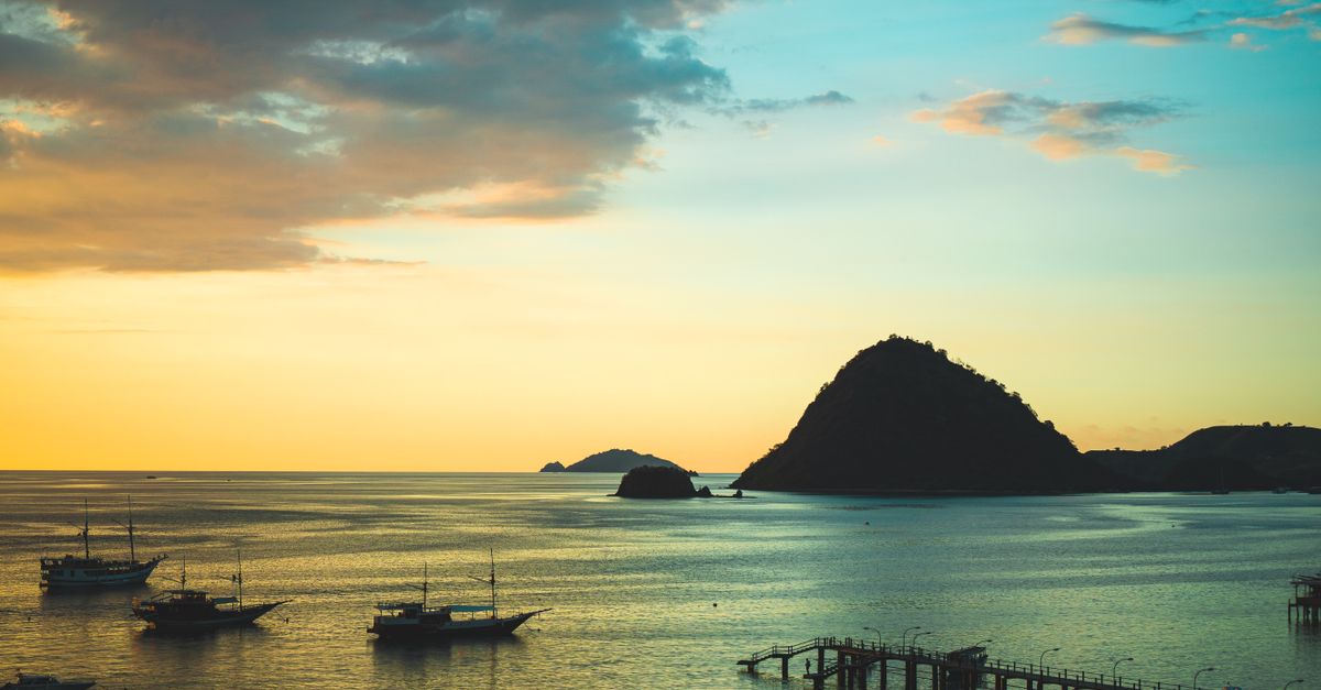 Majestic boats silhouetted against a vibrant sunset in East Nusa Tenggara, Indonesia.