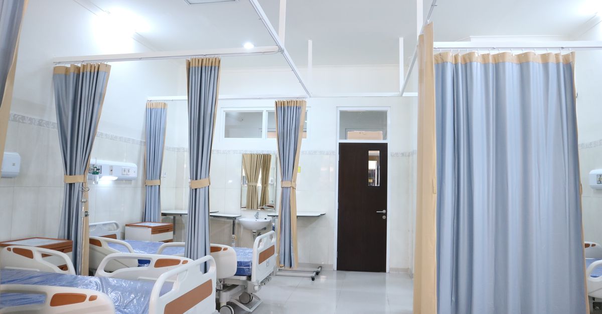 Clean and modern hospital ward with beds and privacy curtains in Surabaya, Indonesia.